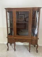 Front view of the restored antique oak display cabinet showing glass front door, wood frame, cabriole legs