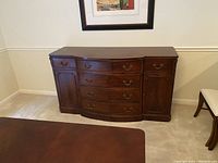 Front view of antique cherry wood sideboard showing 4 center drawers and 2 side doors with brass handles and paneled door fronts.