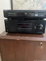 Front view of black Sony 5-disc DVD player on top of Sony AV receiver.