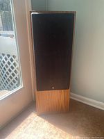 Front view of one Yamaha floor speaker with black fabric grille and wooden base.