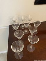 Set of 10 small clear glass stemware wine glasses arranged on a surface, showing bowl shape and slender stems.