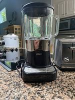 Oster blender with glass jar and black base on kitchen counter