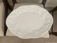 Large white stoneware serving platter with embossed grape and leaf pattern on rim, measuring 15.5 x 21 inches