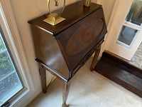 View of traditional reproduction secretary desk showing drop-front and curved legs.