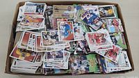 Box filled with around 2000 loose baseball and football cards showing the mixed condition and variety in the lot.