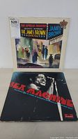 Two James Brown vinyl LP albums, one 'The Apollo Theatre Presents... The James Brown Show' and one 'Sex Machine' album, both with their original covers.