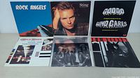 Photo showing Rock Angels, Sting, Goddo, Simple Minds, Queen, and one other LP album with red cover.