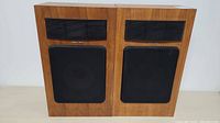 Pair of Realistic MC-2000 speakers side by side showing front wood veneer finish and black grilles
