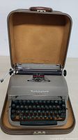 Frontal view of Remington Quiet-Riter typewriter inside open hard shell case showing overall condition and setup.