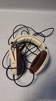 Front angle view of headphones showing padded headband and brown velour ear cushions with attached black audio cable.