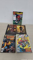 Lot of 5 comic books on table including Wolverine, X-Force, and Spider-Man characters.