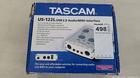 Front of original blue box showing product name, image, and some tech specs for Tascam US-122L USB 2.0 Audio/MIDI Interface.