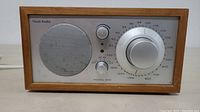 Front view of Tivoli Audio Model One AM FM radio showing speaker grille, tuning dial and control knobs.