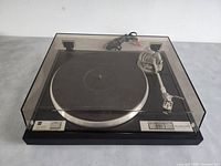 Front view with tinted dustcover closed, showing platter and tonearm