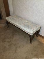 Wooden bench against wall showing full length and top upholstery