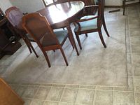 Beige area rug under wooden dining table with chairs on tiled floor, showing size and use context