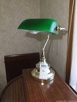 Front view of the lamp showing the green glass curved shade, brass-tone base, pull chain, and lamp height approx. 15 inches.