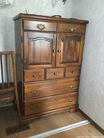 Front view of the tall pine dresser with closed drawers and cabinet doors, showing design and condition.