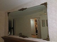 Full view of large rectangular bevelled glass wall mirror showing brass corner and edge decorations
