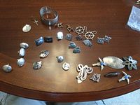 Photo of all sterling silver items spread on table showing multiple pairs of earrings, brooches, cufflinks, and bangle
