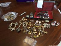 Wide shot of the full collection including watches in a red-lined case, assorted pins, clips, cuff links, whistle, metal frame and multiple Red Cross pins.