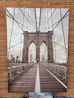 Full view of the large giclee canvas print of Brooklyn Bridge showing the wooden bridge path and suspension cables with city skyline in background.