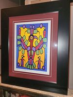 Framed colorful fine art print showing a Thunderbird and two smaller bird figures. The piece is matted in maroon and framed in black.