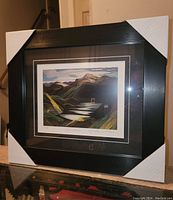 Framed fine art print showing the artwork, matting, and frame with white corner guards on frame edges.