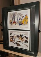 Photo of dual Clarence Gagnon prints titled 'Winter Morning' and 'Village in the Laurentians' in a black frame with matting.