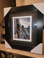 Photo of the full professionally framed print showing the artwork, matting and black frame with corner protectors.