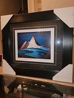 Full view of framed artwork with corner protectors showing the print and frame.