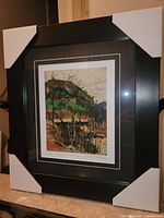 Framed print showing 'Rounded Hill and River' with black frame and corner protectors attached.
