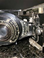 Close-up of lens and aperture shutter control marked Eastman Kodak Co and No 1A Pocket Kodak.