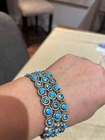 Bracelet shown on wrist displaying turquoise stones set in silver-tone metal and stretchable design.