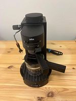 Front view of Braun espresso coffee machine showing control dial, portafilter, glass carafe, and steam wand.