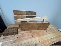 Three wooden floating shelves displayed on a wooden table, showing wood grain and walnut finish. Mounting brackets are visible.