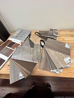Collection of multiple wood grain flooring samples fanned out on a wooden table.
