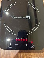 Close-up View of Kuraidori hot plate touch control panel showing heat settings and power button illuminated