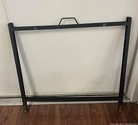 Black metal A-frame sign stand viewed from the front, showing handle at top and rectangular frame shape.