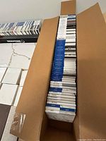 Top view of an open cardboard box containing vertically stacked quartz and granite samples with labels visible on the edges.