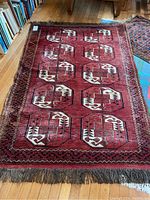 Full view of the rectangular aztec design area rug on hardwood floor, showing overall condition and pattern.