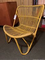 Front angled view showing full chair with bent rattan slats and damage on the seat.