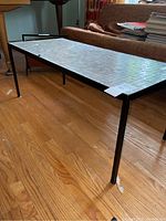 Full side angle view of the rectangular coffee table showing ceramic tile top and black metal legs