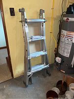 Folded Mastercraft ladder leaning against a wall near basement utilities, showing condition and structural components