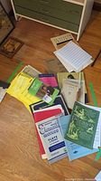 Collection of assorted music instruction and sheet music books on the floor next to a dresser showing size and variety.