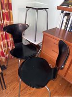 Pair of black wood retro chairs with metal legs around a vintage folding TV tray/side table and a matching metal stool.