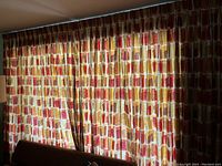 Full view of yellow, orange, and red geometric block curtains hanging closed covering windows.