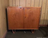 Front view of the wooden cabinet showing two closed doors and curved legs.