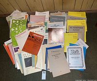 Top down view of a large collection of sheet music booklets and sheets spread on the floor showing titles by Wolfgang Fortner, Antonio Vivaldi, Handel, among others.
