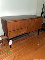 Front-side angle view showing cabinet profile, hinged cubby compartments closed, and open shelf below.